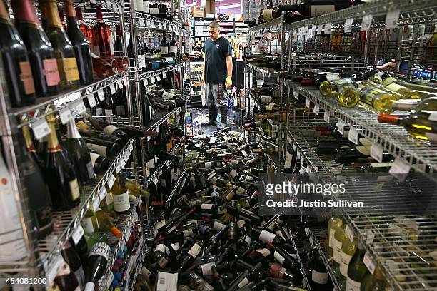 Worker looks at a pile of wine bottles that were thrown from the shelves at Van's Liquors following a reported 6.0 earthquake on August 24, 2014 in...