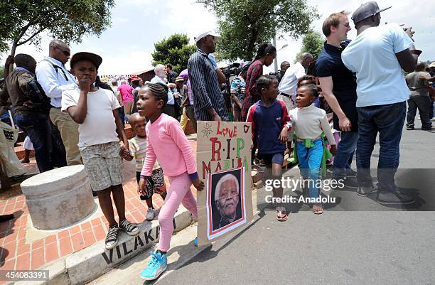 South African children with a placard showing the face of Nelson Mandela walk along Vilakazi street outside of Nelson Mandela's family house to show...