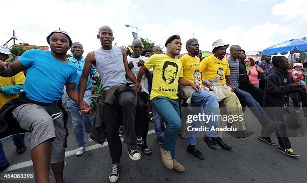 Local people walk along Vilakazi street outside of Nelson Mandela's family house to show their respect for him on December 6, 2013 in Soweto,...