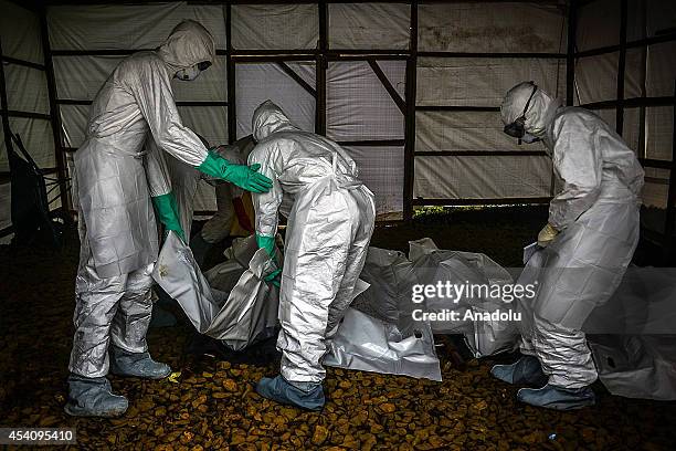 Group of young volunteers wear special uniforms to put the bodies of people, sterilized after dying due to the Ebola virus, to a car ahead of their...