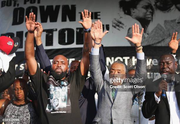 Michael Brown Sr. And Civil rights leader Rev. Al Sharpton hold up their hands as attorny Benjamin Crump speaks at Peace Fest music festival in...