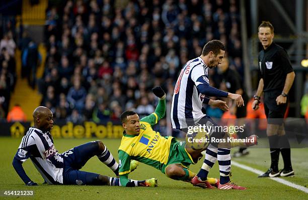 Martin Olsson of Norwich is challenged by Youssouf Mulumba and Diego Lugano of WBA during the Premier League match between West Bromwich Albion and...