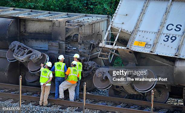 Workers stand near one of the coal cars of the derailed train behind the Baltimore & Ohio Railroad Museum: Ellicott City Station on Tuesday, August...
