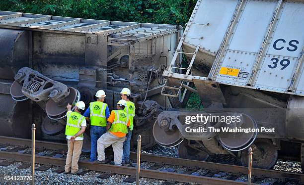 Workers stand near one of the coal cars of the derailed train behind the Baltimore & Ohio Railroad Museum: Ellicott City Station on Tuesday, August...