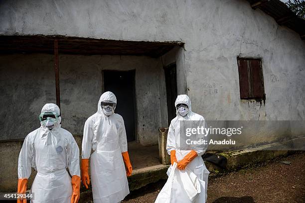 Group of young volunteers wear special uniforms sterilize round the house after Baindu Koruma died due to the Ebola virus, in Lango village, Kenema,...