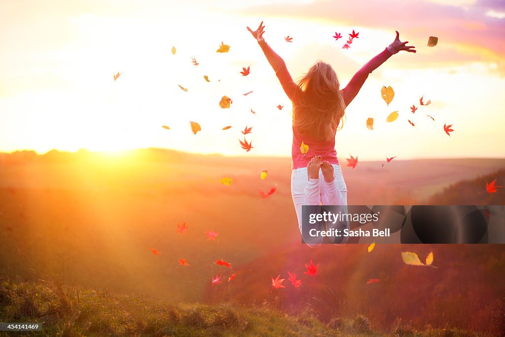 Woman Jumping at Sunset with Autumn Leaves