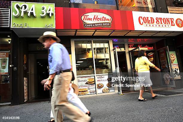 People walk past a Tim Horton's cafe in Manhattan on August 25, 2014 in New York City. It has been confirmed that American fast food giant Burger...