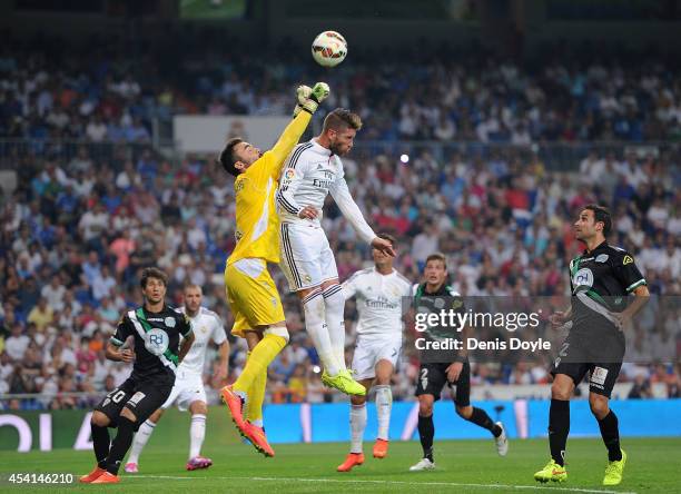 Juan Carlos of Cordoba CF gets his fists to the ball ahead of Sergio Ramos of Real Madrid CF during the La liga match between Real Madrid CF and...