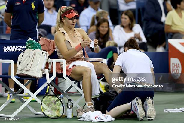 Maria Kirilenko of Russia gets worked on by a trainier while playing against Maria Sharapova of Russia during her women's singles first round match...