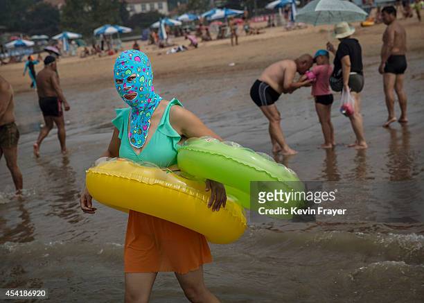 Chinese woman wears a face-kini as she walks into the water to swim on the beach on August 22, 2014 on the Yellow Sea in Qingdao, China. The locally...