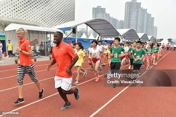 Former high jumper Kajsa Bergqvist of Sweden and World Long Jump champion Dwight Phillips of United States lead children to warm up during the IAAF...