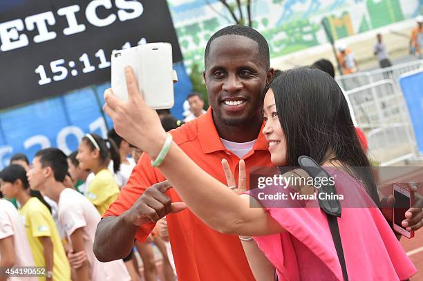 World Long Jump champion Dwight Phillips of United States takes a selfie with a girl during the IAAF Kids Athletics Program at Yanshan Road on August...