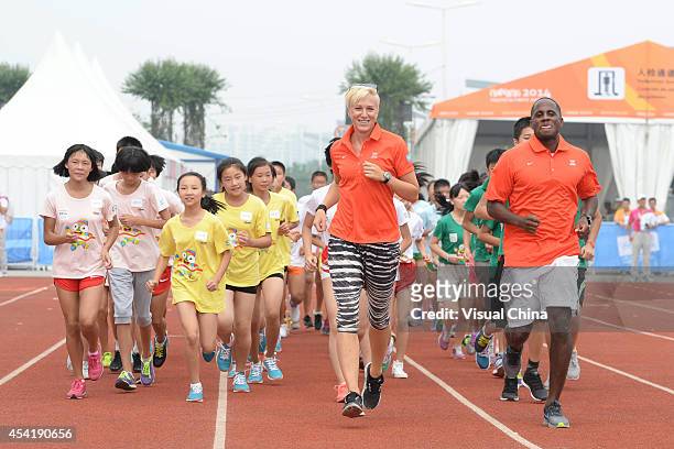 Former high jumper Kajsa Bergqvist of Sweden and World Long Jump champion Dwight Phillips of United States lead children to warm up during the IAAF...