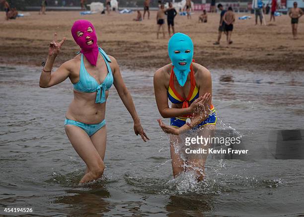 Chinese women wear face-kinis as they walk in to the water to swim at the beach on August 20, 2014 in the Yellow Sea in Qingdao, China. The locally...