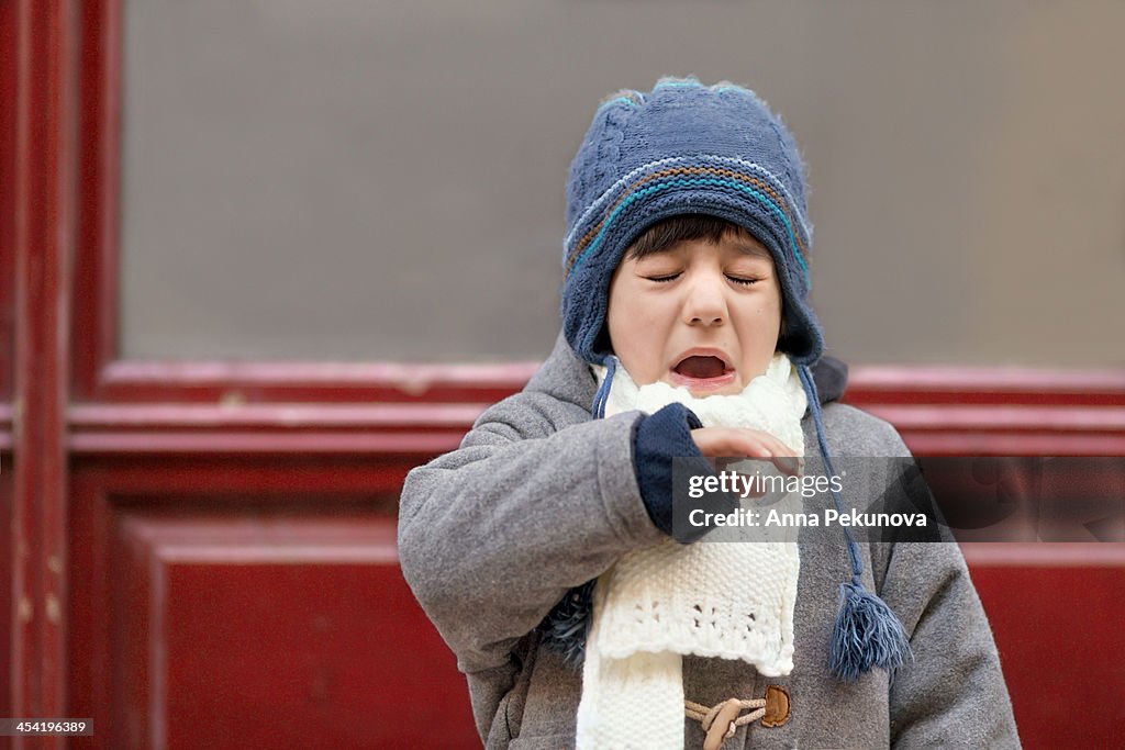 Outdoor portrait of sneezing boy