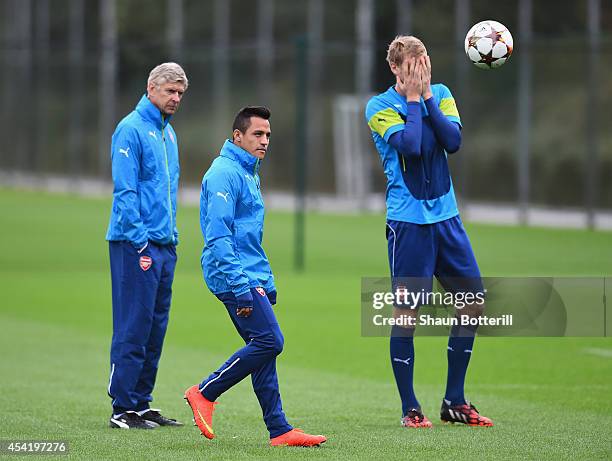 Alexis Sanchez of Arsenal passes the ball as manager Arsene Wenger and Per Mertesacker look on during a training session at London Colney on August...