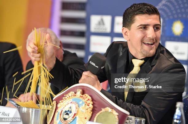 Marco Huck crushes spaghetti during the press conference at Lenkwerk on August 26, 2014 in Bielefeld, Germany. The WBO World Championship...