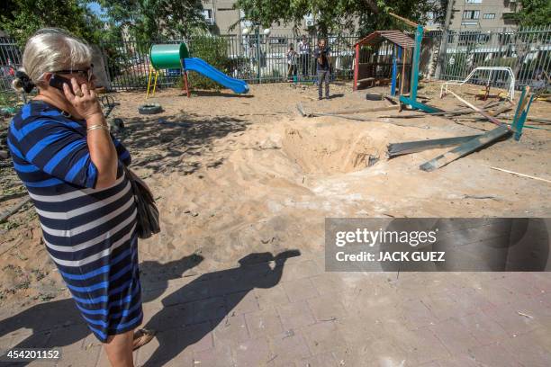 An Israeli woman talks on her phone next to a crater caused by a rocket, fired by Palestinian militants from the Gaza Strip, after it landed in the...