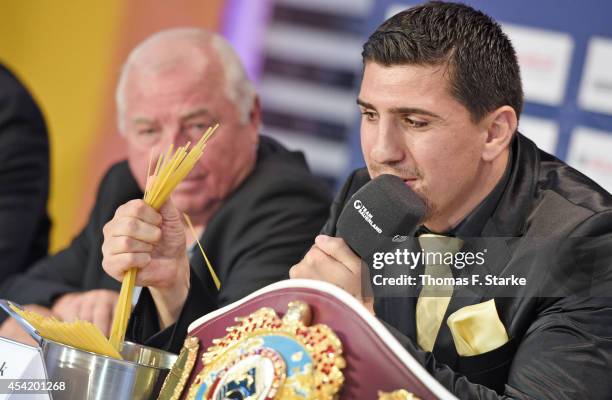 Marco Huck crushes spaghetti while his coach Ulli Wegner looks on during the press conference at Lenkwerk on August 26, 2014 in Bielefeld, Germany....