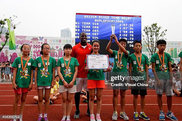 World Long Jump champion Dwight Phillips of United States pose with children during the IAAF Kids Athletics Program at Yanshan Road on August 26,...