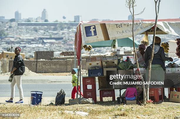 South African street vendor trades with customers in Alexandra Township on the backdrop of the Sandton Towers, one of Africa's leading and most...