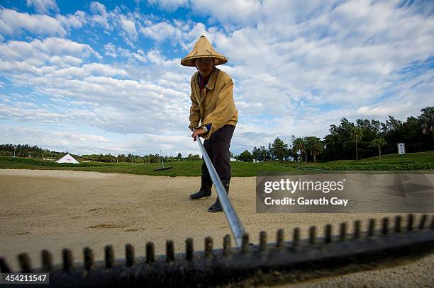 Grounds man, rakes the sand of the bunker on the eighteen course, in the early hours before of the last day of the Swinging Skirts 2013 World Ladies...