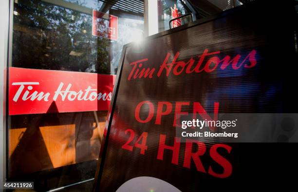 An "Open 24 Hours" sign is displayed outside of a Tim Hortons Inc. Restaurant in downtown Vancouver, British Columbia, Canada, on Tuesday, Aug. 26,...