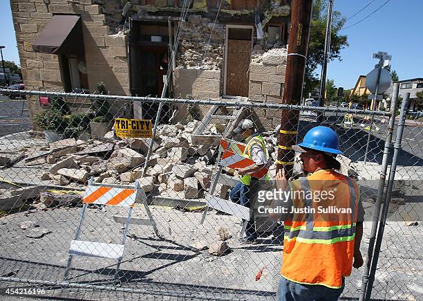 Workers erect a fence around the earthquake-damaged Vintner's Collective building on August 26, 2014 in Napa, California. Two days after a 6.0...