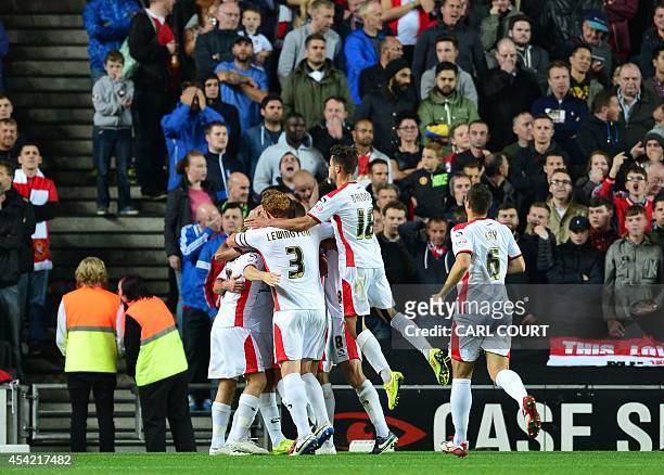 Dons players celebrate their first goal in front of Manchester United's supporters during the English League Cup second round football match between...