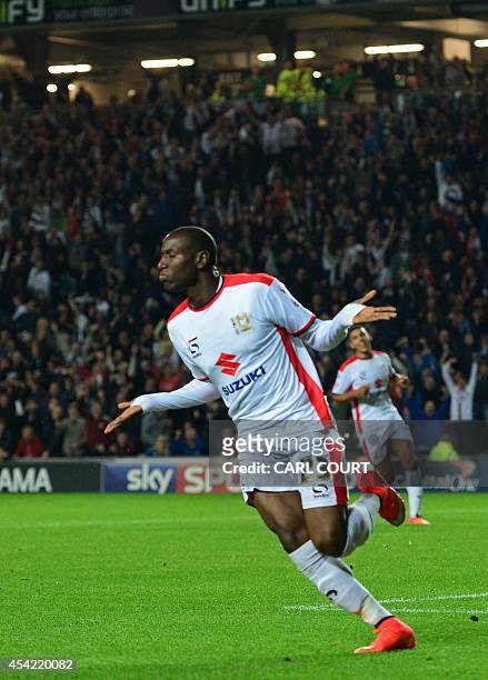 Dons English striker Benik Afobe celebrates scoring their third goal during the English League Cup second round football match between Milton Keynes...