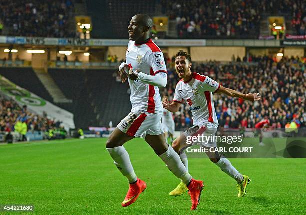 Dons English striker Benik Afobe celebrates scoring their third goal during the English League Cup second round football match between Milton Keynes...