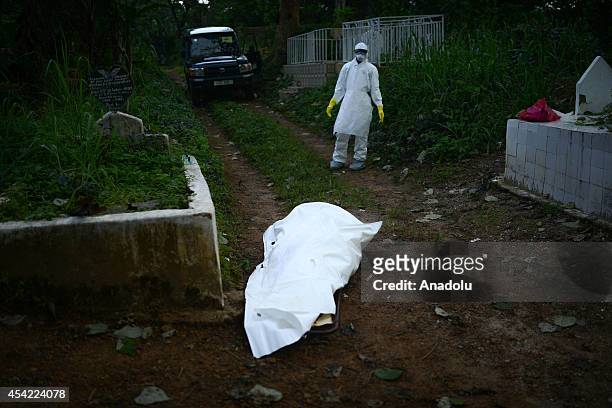 Member of a volunteer medical team in special uniform, stands near the body of an Ebola victim during the burial of 7 people died due to the Ebola...