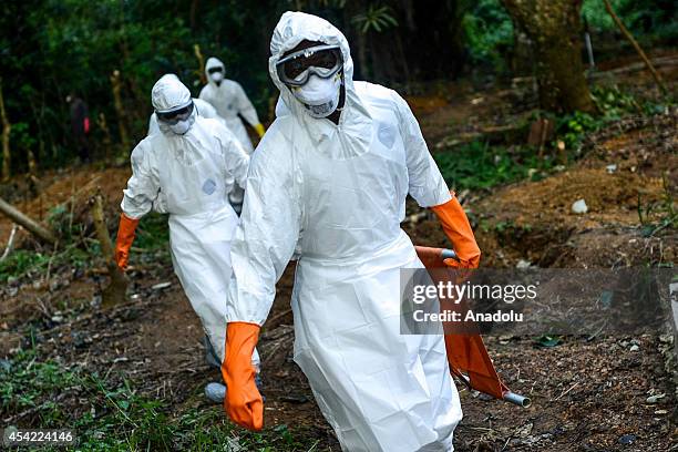 Members of a volunteer medical team wear special uniforms for the burial of 7 people, sterilized after dying due to the Ebola virus, in Kptema...