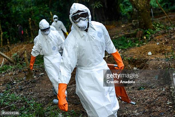 Members of a volunteer medical team wear special uniforms for the burial of 7 people, sterilized after dying due to the Ebola virus, in Kptema...