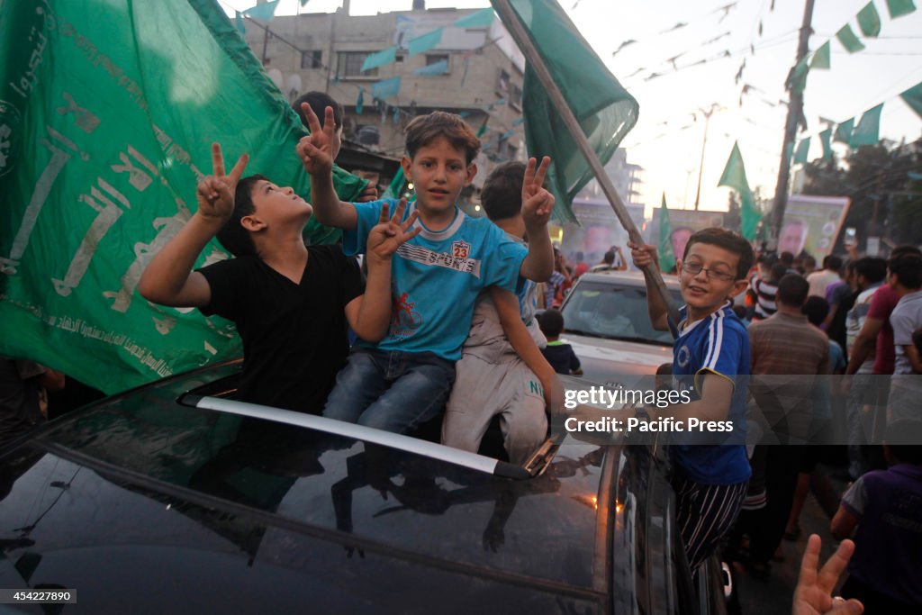 Palestinian children flashing sign of victory atop a car as...