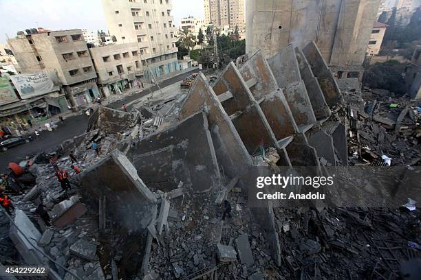 Palestinians inspect the rubble of 15-storey Basha Tower, one of the tallest buildings in Gaza City containing flats and offices, that partially...