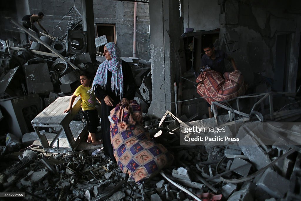 Palestinian residents salvage items from the remains of...