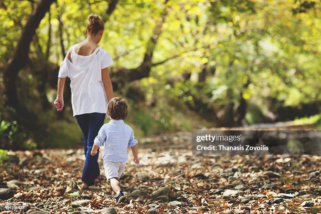 Small boy with his mother walk in the forest