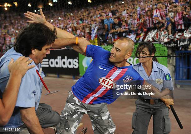 Club Atletico de Madrid fan is pulled from the field of play by security at the end of the Supercopa, second leg match between Club Atletico de...