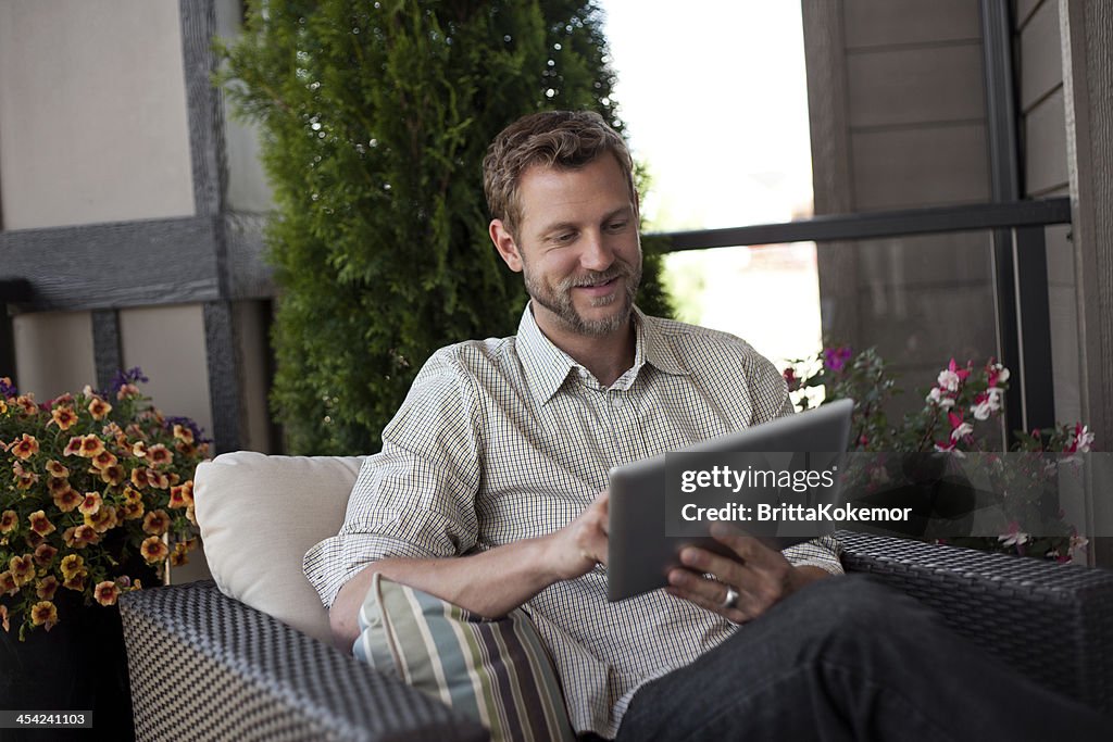 Smiling man with digital tablet sitting outside