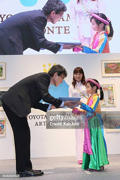 Bui Thanh Mai of Vietnam , winner of under 8 years old world contest award, accepts her award from Shoju Nozaki, Executive director of Toyota Motor...