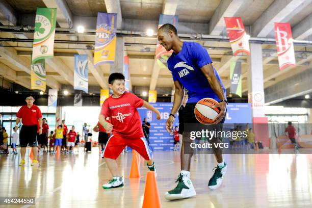 Player Rajon Rondo of the Boston Celtics plays basketball with children at the NBA Yao School on August 27, 2014 in Beijing, China.