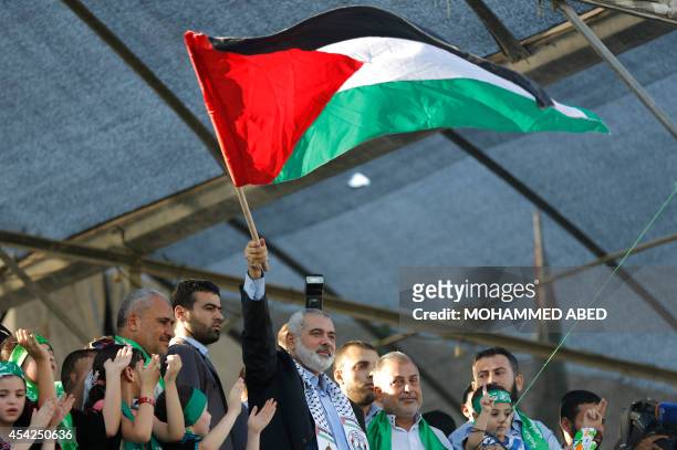 Hamas top leader in the Gaza Strip Ismail Haniya waves the Palestinian flag during a rally in Gaza City on August 27 following a deal hailed by...