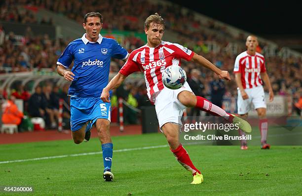 Marc Muniesa of Stoke City clears from Joe Devera of Portsmouth during the Capital One Cup Second Round match between Stoke City and Portsmouth at...