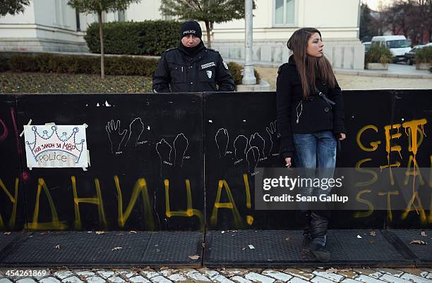 Young woman leans against a barrier spray-painted by activists protesting against government and police corruption in front of the Bulgarian...