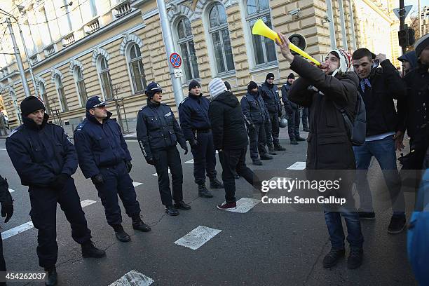 An activist protesting against government and police corruption blows into a vuvuzela next to a line of police on December 5, 2013 in Sofia,...