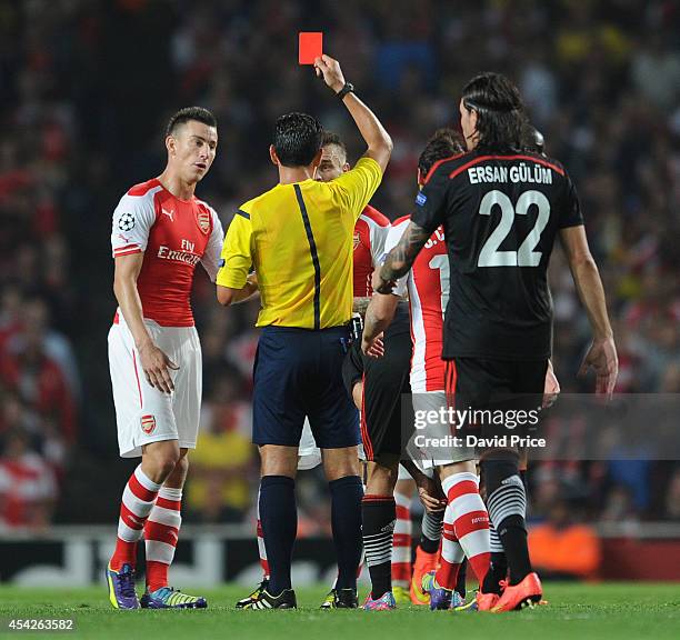 Mathieu Debuchy of Arsenal is shown the red card by Referee Pedro Proenca as Laurent Koscielny of Arsenal looks on during the UEFA Champions League...