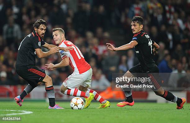 Jack Wilshere of Arsenal takes on Ersan Gulum and Mustafa Pektemek of Besiktas during the UEFA Champions League Qualifing match between Arsenal and...