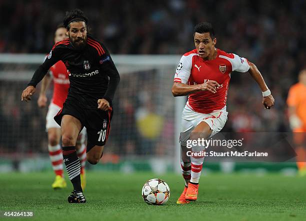 Alexis Sanchez of Arsenal breaks past Olcay Sahan of Besiktas during the UEFA Play Off match between Arsenal and Besiktas at Emirates Stadium on...