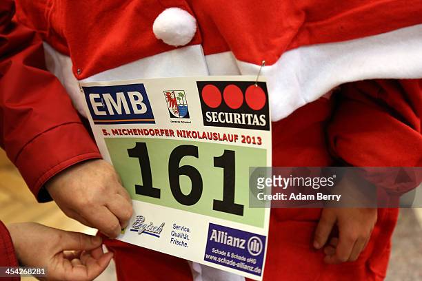 Child participant receives assistance in pinning on his number for 5th annual Michendorf Santa Run on December 8, 2013 in Michendorf, Germany. Over...
